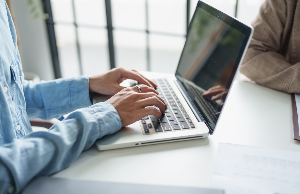 A person typing on a laptop on a desk.